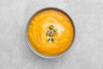 Bowl of tasty pumpkin cream soup on grey background
