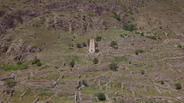 An old tower in the middle of the North Caucasus mountains. Ruind city in the middle of the majestic mountains. Aerial shot