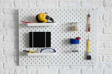 Peg board with construction tools hanging on wall