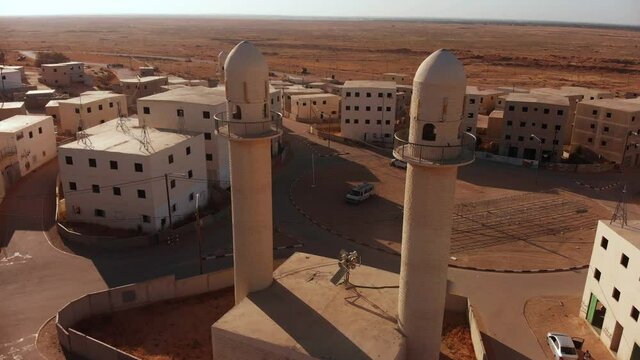 aerial shot of two mosques next to the main squere in an old empty city in the desert in palestine near Gaza at sunset.