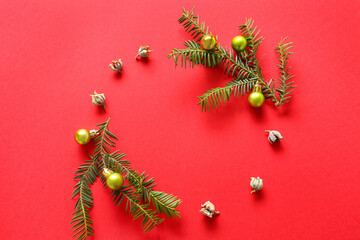 Frame made of fir branches, cones and Christmas balls on red background