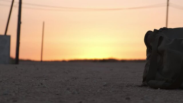 close-up of army bag on the ground in the desrt at the sunset,