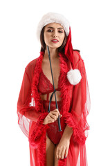 Sexy young woman in Santa hat and underwear holding whip on white background