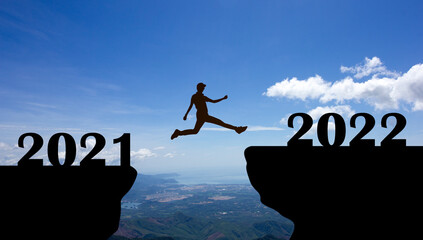 silhouette of person jump from 2021 to 2022 with blue sky background, Concept better future and...