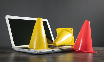 Yellow and red traffic cones on laptop keyboard.