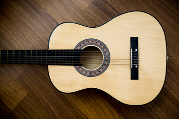 Classical guitar lies on wooden background.