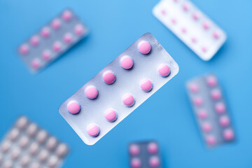 Flying pink pills in a blister pack on blue background. Medicine and healthcare concept