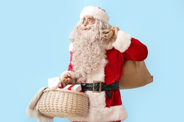 Santa Claus with bag, basket and presents on blue background