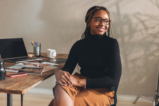 Contemplative young woman smiling in her home office