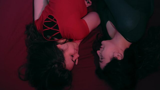 upside down portrait of young lesbians on the bed caresse and hug each other