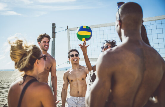 Storytelling image of a group of friends spending time in Santa Monica playing and having fun. Multiethnic young people from california reunited on the beach during a summer day.