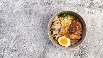 Japanese ramen with pork belly, mushrooms and marinated eggs in a a bowl on a dark grey background....