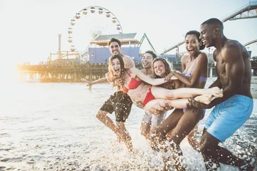 Fotobehang Storytelling image of a group of friends spending time in Santa Monica playing and having fun. Multiethnic young people from california reunited on the beach during a summer day. © oneinchpunch