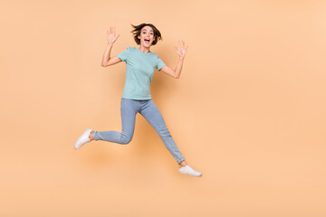 Fototapeta na wymiar Full length photo of young girl have fun jump up wave hi friendly travle dream isolated over beige color background