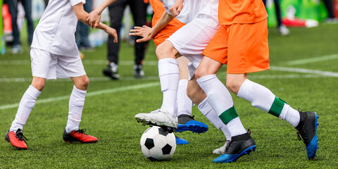 Obraz premium Background image of football game. Legs of soccer players kicking vlack and white soccer ball on artificial grass pitch. Soccer coach on sideline