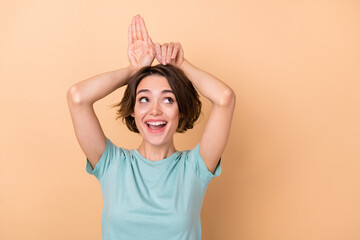 Photo of young pretty girl good mood look empty space show arms animal ears isolated over beige color background