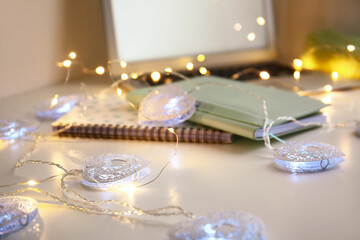 Christmas lights and notebooks on table, closeup
