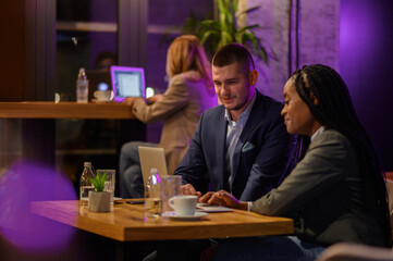 Two business people having a meeting in a cafe while using a laptop