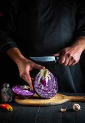 The chef cuts red cabbage with a knife. Cooking vegetable salad in the restaurant kitchen. Vegetable diet idea.