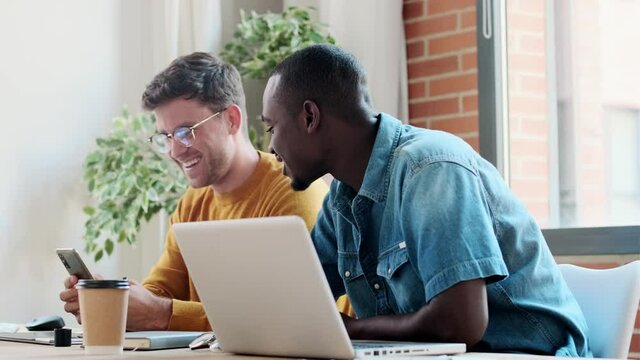 Video of two graphic designer working with laptop while celebrating something shaking hands in modern startup office.