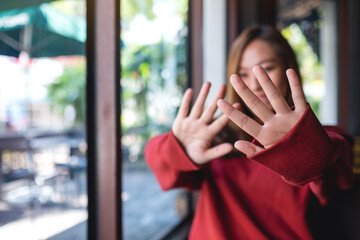 A young asian woman outstretched hand and showing stop hand sign