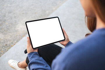 Mockup image of a woman holding digital tablet with blank white desktop screen in the outdoors