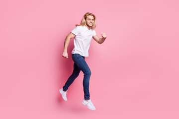 Fototapeta na wymiar Full size photo of charming young happy man jump up run empty space good mood isolated on pink color background