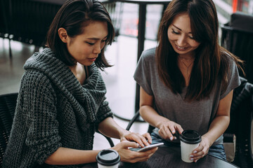 Two japanese women around in Tokyo during daytime. Making shopping and having fun