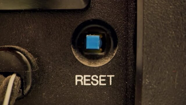 Extreme close up of a button on a vintage VCR.  Pushing a blue reset button