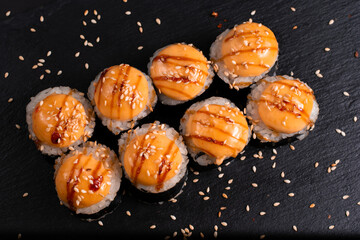 Set of baked sushi rolls on a black background. Japanese oriental cuisine