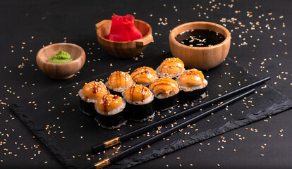 Set of baked sushi rolls with wasabi and ginger on a black background. Japanese oriental cuisine © imdproduction