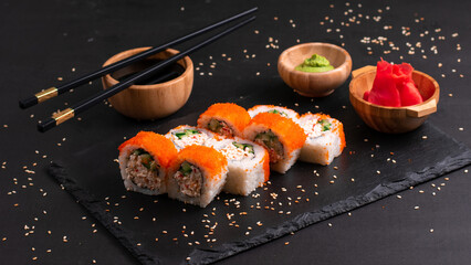 California roll maki sushi. Tasty fresh sushi rolls with salmon on black background. Japanese oriental cuisine