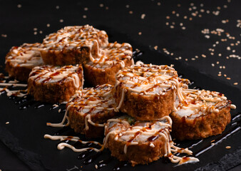 tempura sushi rolls made of smoked. Tasty fresh sushi rolls with salmon on black background. Japanese oriental cuisine