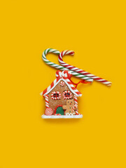 Gingerbread house, red clock, gift, lollipop, candy on a yellow background.