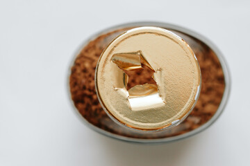 Top view of a glass jar of coffee without a lid, the gold-colored label is torn, the integrity of the packaging is broken, the background. Close-up.
