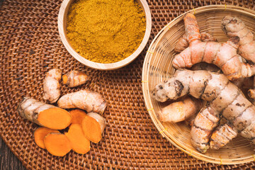 Turmeric Powder and Turmeric root on bamboo mat, Curry Powder on a wooden table background.