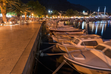 Fototapeta na wymiar Waterfront promenade and moored boats in tourist resort Baska Voda on Adriatic sea coast in Croatia, at night in summer
