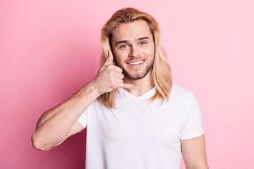 Photo of attractive young happy man hold hand make gesture call me good mood isolated on pink color background