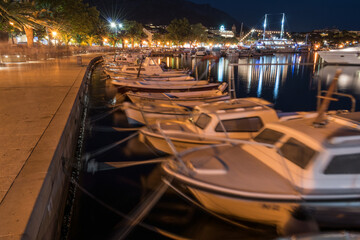 Waterfront promenade and moored boats in tourist resort Baska Voda on Adriatic sea coast in Croatia, at night in summer