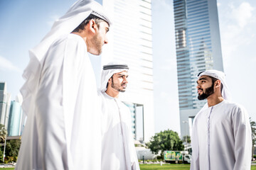 Image of a group of friends from the emirates meeting in Dubai.  Young adults wearing the traditional local white dress spending time in the city center. Concept about middle eastern cultures 