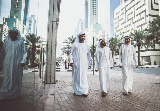 Image of a group of friends from the emirates meeting in Dubai.  Young adults wearing the traditional local white dress spending time in the city center. Concept about middle eastern cultures 