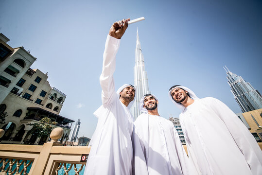 Image of a group of friends from the emirates meeting in Dubai.  Young adults wearing the traditional local white dress spending time in the city center. Concept about middle eastern cultures 