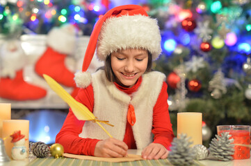 Portrait of happy girl writing letter to Santa Claus