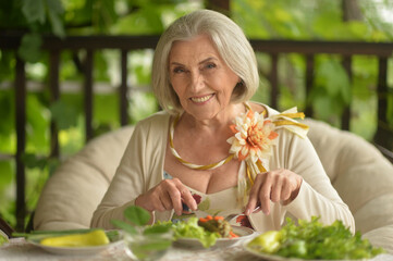 Portrait of happy senior woman eating delicious salad