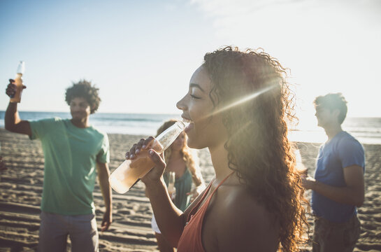 Group of friends having fun on the beach in Los angeles. Storytelling image of multiethnic people making a bone fire and barbeque at sunset. Spending a summer day in california