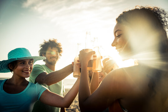 Group of friends having fun on the beach in Los angeles. Storytelling image of multiethnic people making a bone fire and barbeque at sunset. Spending a summer day in california