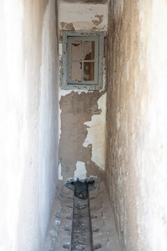 Very narrow room with a drain and a broken window. Abandoned building during the war