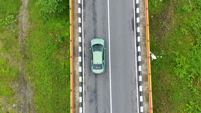 Car crossing bridge over Luk Ulo river in Indonesia. Tracking aerial top-down view