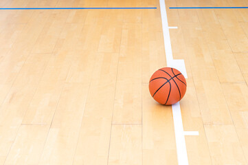 Basketball on hardwood court floor with natural lighting. Workout online concept. Horizontal sport...