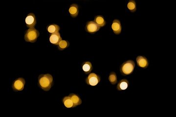 Bokeh golden lights background. Blurred lights Christmas garland isolated on a black background.